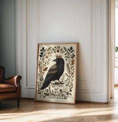 a black bird sitting on top of a wooden floor next to a chair and window