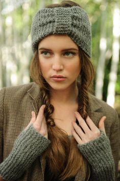 a woman with long hair wearing a hat and holding her hands in front of her face