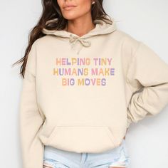 Wrap yourself in warmth with this "Helping Tiny Humans Make Big Moves" sweatshirt, perfect for pediatric nurses, pediatricians, and daycare teachers making a difference every day. This cozy hoodie also makes a thoughtful Christmas gift for anyone in OT, PICU, or labor and delivery who loves working with little ones! Prefer this design on a T-Shirt? Visit this link:  Everything You Need to Know: 🧥 Sweatshirt Brand Gildan | Unisex Adult Sizing ⏳🚚 Production & Shipping All items are made-to-order. They will ship within 1-5 business days from one of our printing partners, shipping usually takes between 2-5 business days after the item is shipped. Please allow sufficient time for production and shipping.  Important: Please double-check your shipping address before checking out. A fee will app Peds Nurse, Nurse Tote Bag, Picu Nurse, Nurse Tote, Labor And Delivery Nurse, Daycare Teacher, Nursing Hoodie, Delivery Nurse, Pediatric Nurse