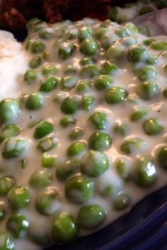 green peas are covered with white sauce in a casserole dish on a plate