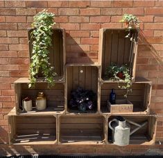 several wooden crates with plants growing out of them on the side of a brick wall