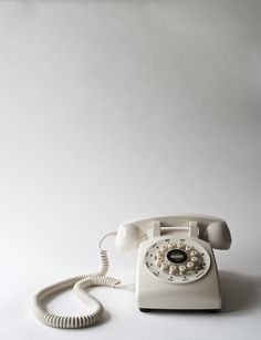 an old - fashioned phone is sitting on the floor in front of a white wall