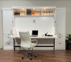 an office desk with a laptop on it in front of a bookcase and cabinets