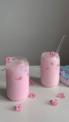 two jars filled with pink liquid sitting on top of a table next to a book