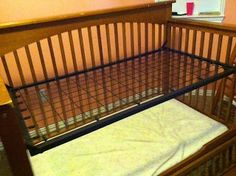 a wooden crib with a mattress in it