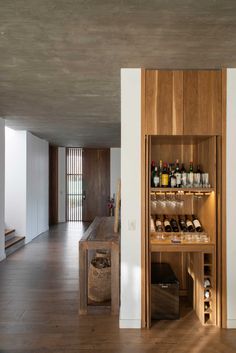 a wooden shelf filled with lots of bottles next to a kitchen counter and stairs in front of it