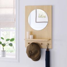 a wall mounted shelf with a mirror and hat on it next to a potted plant