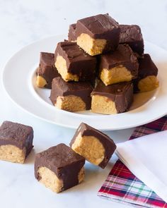 several pieces of chocolate peanut butter fudge on a white plate next to other pieces