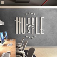 an office with multiple computers and chairs in front of a wall that says stay humble hard