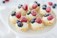 small cupcakes with berries and powdered sugar on a white cake plate, ready to be eaten