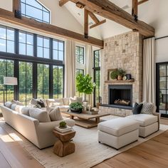 a living room filled with lots of furniture next to a fire place and large windows