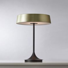 a lamp that is sitting on top of a table in front of a white wall