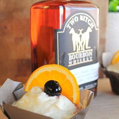 a cupcake with an orange slice on it next to a bottle of bourbon whiskey