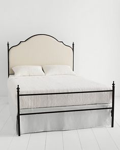 a white bed with black frame and headboard in a room that has white floors