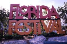 there is a sign that says florida festival in front of some rocks and trees with bushes around it