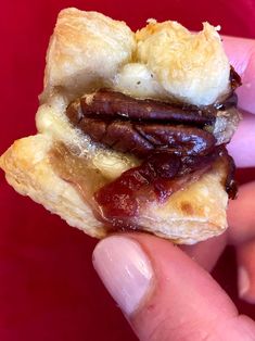 a person holding up a pastry with sausage on it