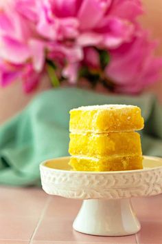 three pieces of cake sitting on top of a white plate with pink flowers in the background