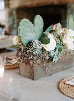 an arrangement of flowers and succulents in a wooden box on a table