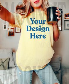 a woman holding a coffee mug in her right hand and wearing a t - shirt that says your design here