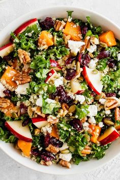 a white bowl filled with salad topped with apples and nuts