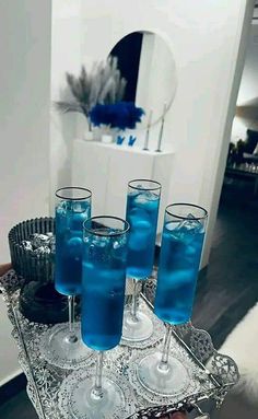 there are four glasses on the tray with blue liquid