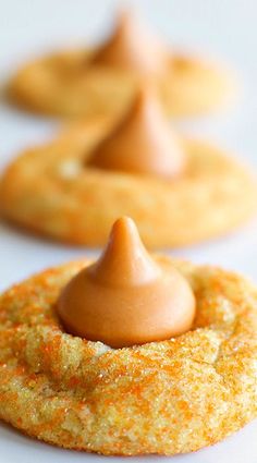 some cookies with icing on them are sitting on a white tablecloth and there is an orange sauce in the middle