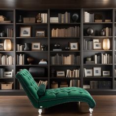 a green chaise lounge chair sitting in front of a bookshelf