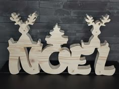 a wooden sign that says noel with two reindeers on it and the word noel written in large letters