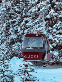 a red ski lift going up the side of a snow covered mountain with trees in the background