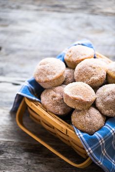 a basket filled with powdered donuts on top of a blue and white checkered cloth