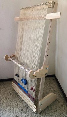 an old weaving machine sitting on the floor in front of a white wall and carpeted floor