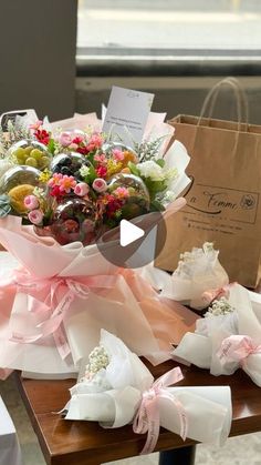 a bouquet of flowers sitting on top of a wooden table next to a brown bag