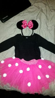 a pink and black minnie mouse outfit with polka dots on the bottom is laying on a bed