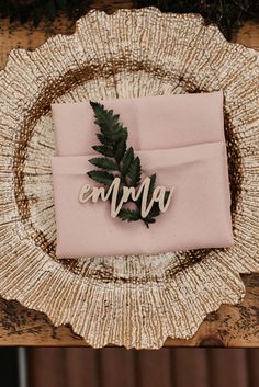 a place setting with pink napkins and greenery on it, along with the word enjoy