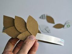 someone is holding up a piece of paper with leaves on it that are cut out of cardboard