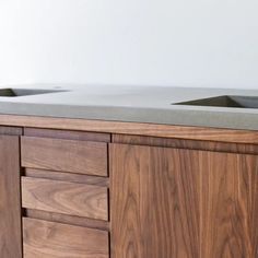 two black sinks are on top of a wooden cabinet with grey counter tops and drawers