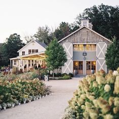 a large white building surrounded by lots of trees and flowers in front of it's entrance