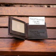 an empty wallet sitting on top of a wooden bench next to a note that says happy 50th anniversary