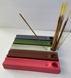 four different colored incense sticks in a holder