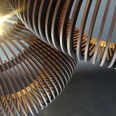 an abstract sculpture made out of wood and metal strips with the sun shining through it