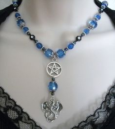 "This beautiful necklace has blue faceted beads, black rhinestone beads, seed beads, pewter silver accent beads, sterling silver plated bead caps, pewter silver pentacle and pewter silver dragon. 18\" long. Toggle clasp." Gothic Dangle Necklaces For Jewelry Making, Handmade Gothic Blue Necklace, Handmade Blue Gothic Necklace, Gothic Beaded Jewelry For Halloween, Gothic Beaded Halloween Jewelry, Halloween Festival Jewelry With Black Beads, Adjustable Gothic Beaded Jewelry, Halloween Festival Black Beaded Jewelry, Mystical Blue Jewelry For Festivals