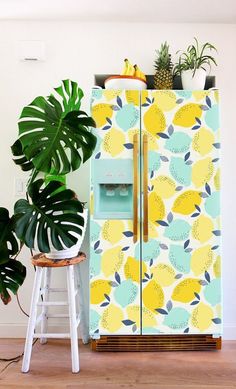 a yellow and blue refrigerator next to a potted plant