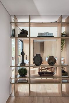 a wooden shelf filled with vases on top of a hard wood floor next to a window