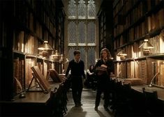 two people are walking through an old library