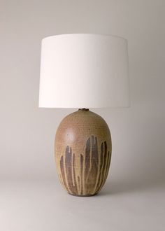 a brown and white vase sitting on top of a table next to a white lamp