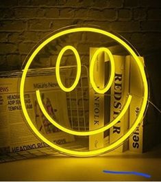 a yellow smiley face light sitting on top of a table next to a pile of books