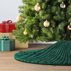 a christmas tree with presents under it and a blanket on the floor next to it