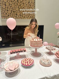 a woman standing in front of a table filled with cakes and desserts