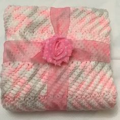 a pink and white blanket with a flower on it