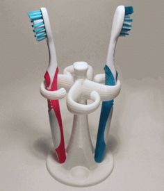 three toothbrushes in a holder on a white table top, one is blue and the other is red